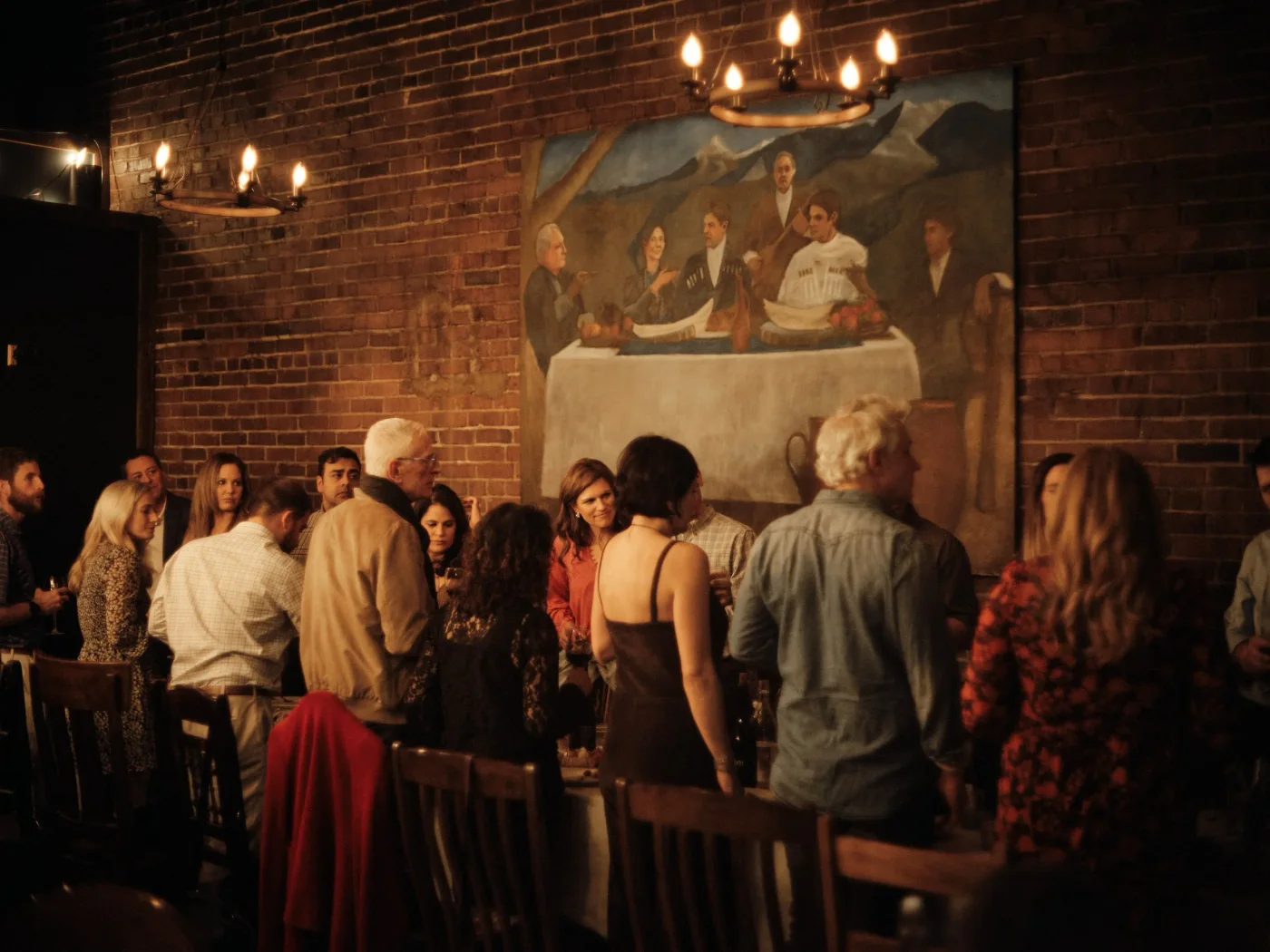 Guests talking together among the tables, beneath a painting of a Georgian feast.