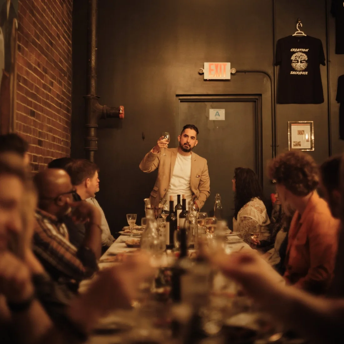 A man raises his glass as guests listen around a long table at Keipi.