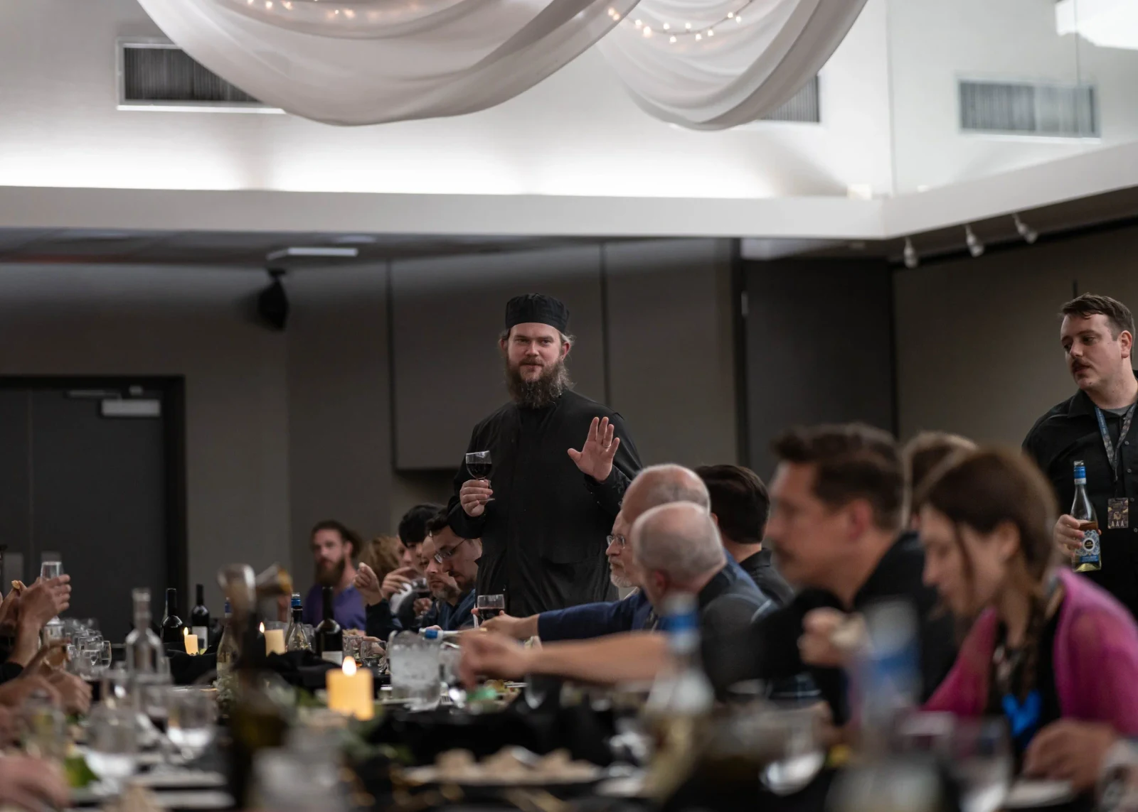 A table leader speaks to guests gathered in a large room.